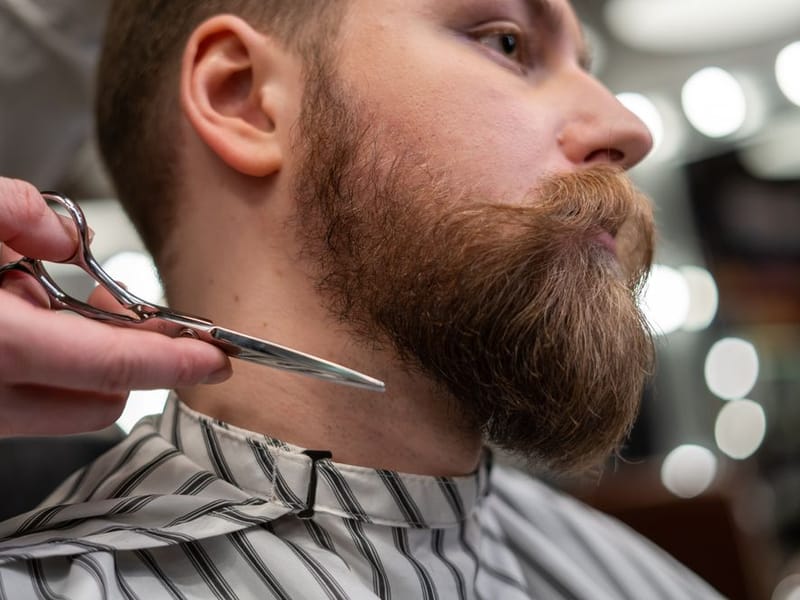 Barber applying a subtle colour blend to soften grey at a client’s temples
