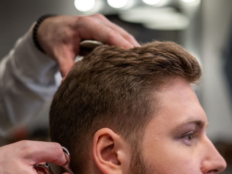 Barber giving a smooth razor head shave with a hot towel nearby